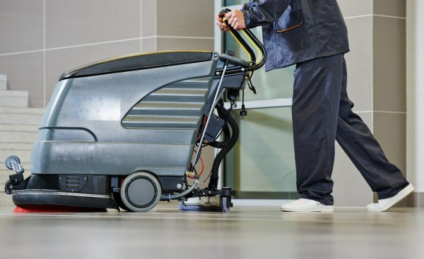Worker Cleaning Floor With Machine